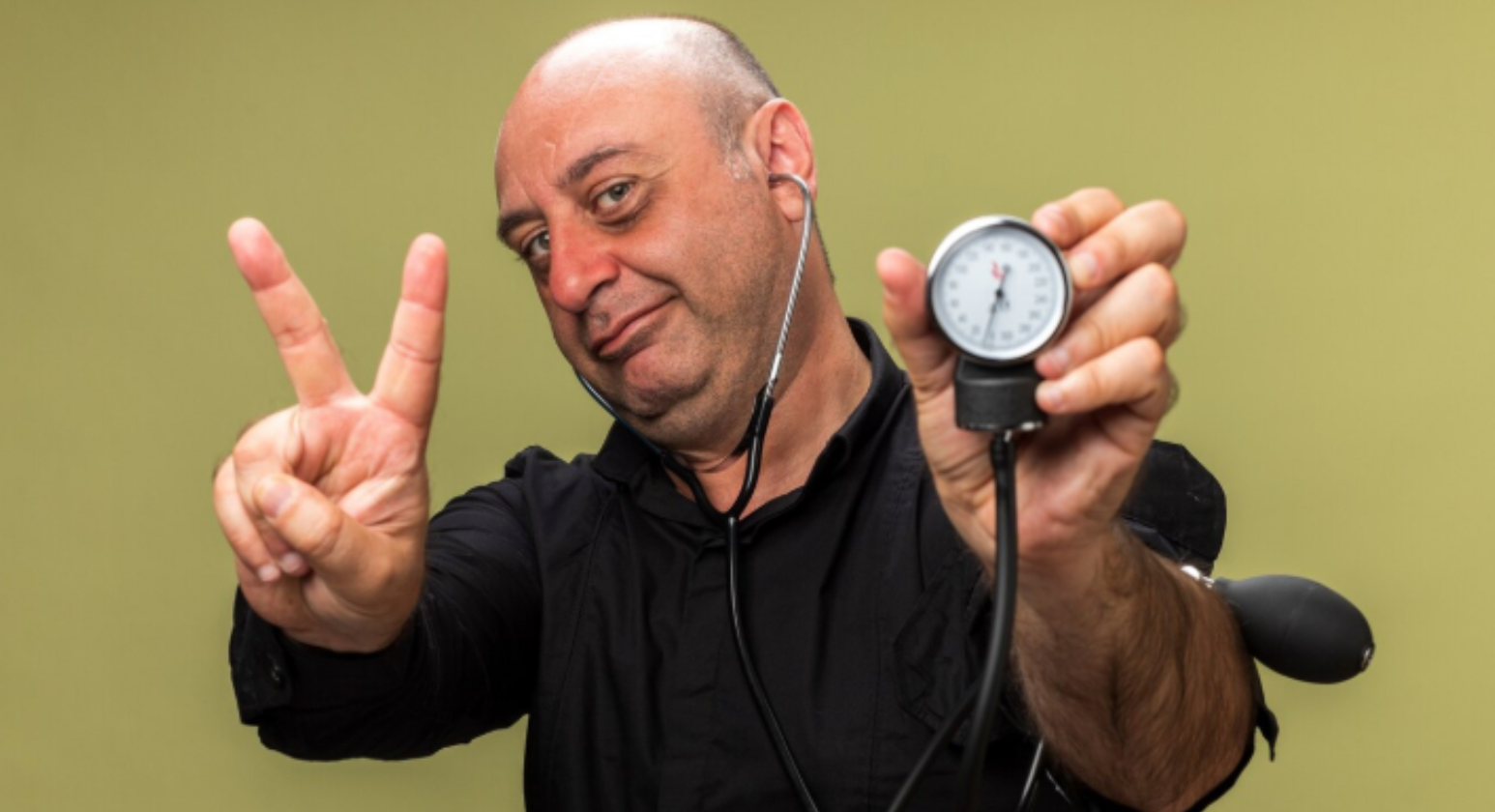 Confident man holding a blood pressure gauge and making a peace sign, suggesting healthy blood pressure and wellness support.