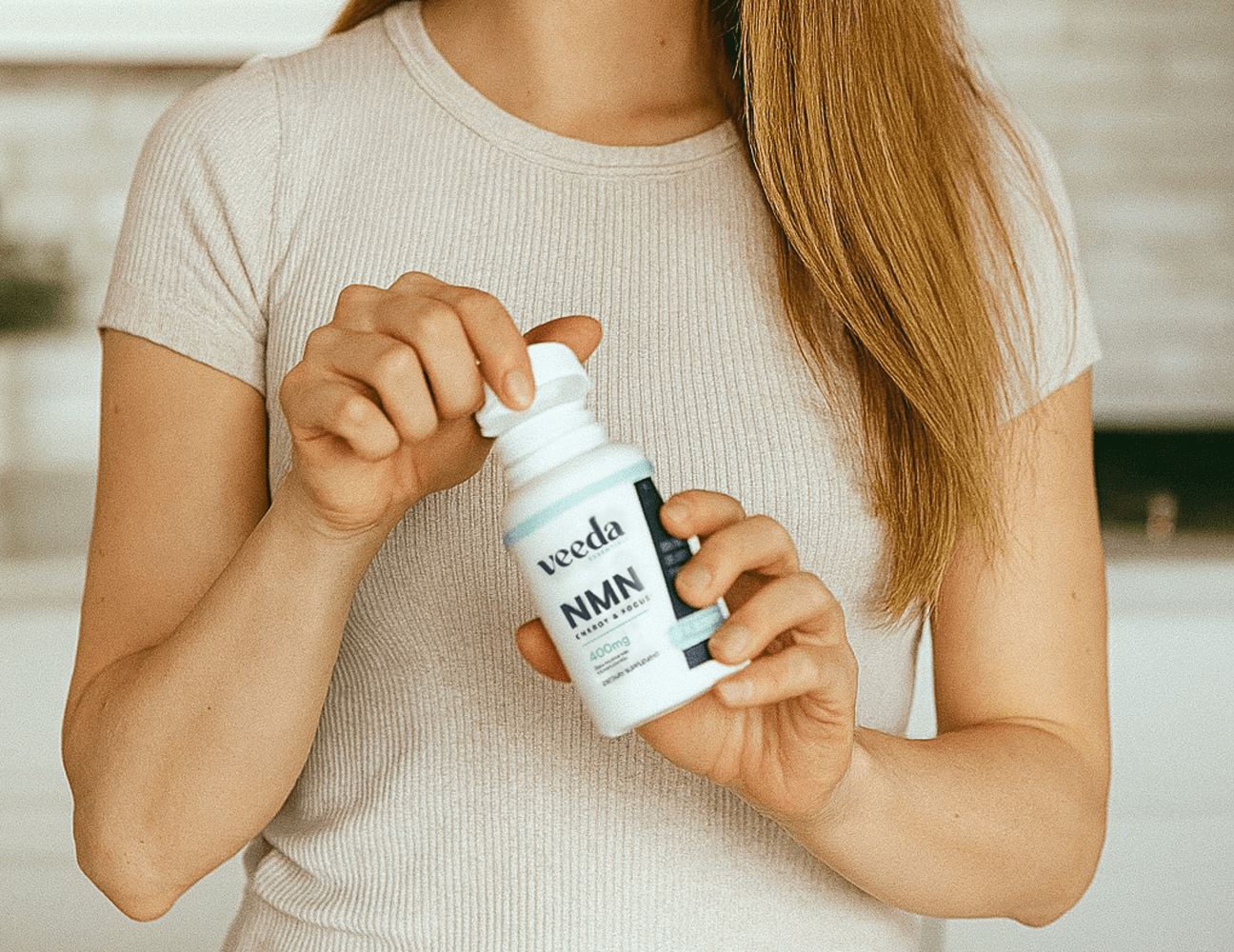 Person holding a Bottle veeda essentials NMN energy and focus supplement in a neutral setting