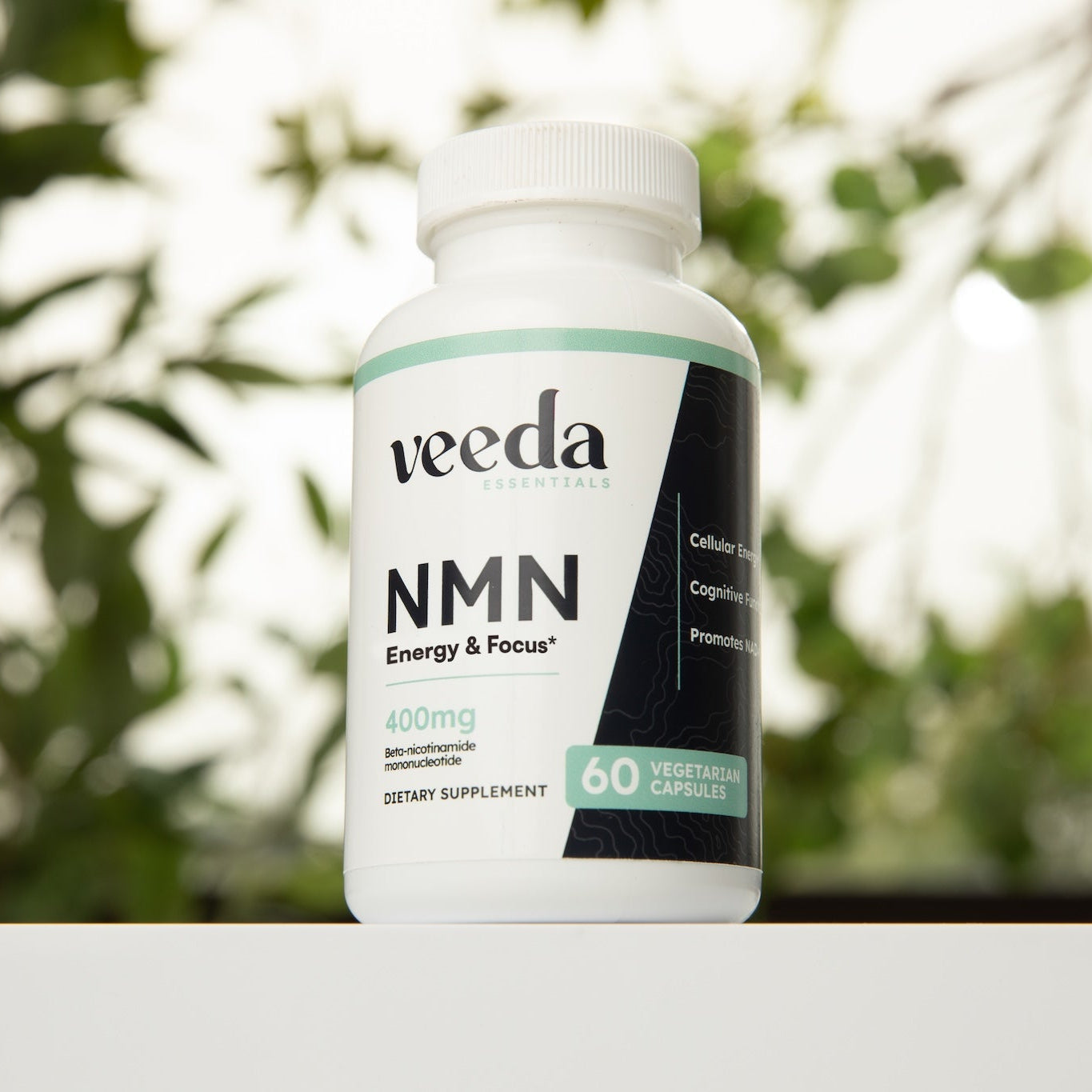 Veeda NMN supplement bottle on a white surface with a blurred green background