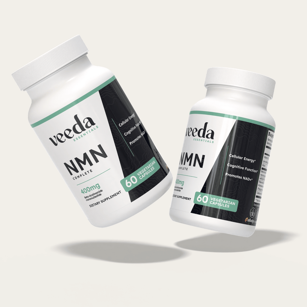 Two Veeda Essentials NMN Complete supplement bottles elegantly floating, representing scientifically-backed ingredients for sustained cellular energy, clear thinking, and NAD+ support.
