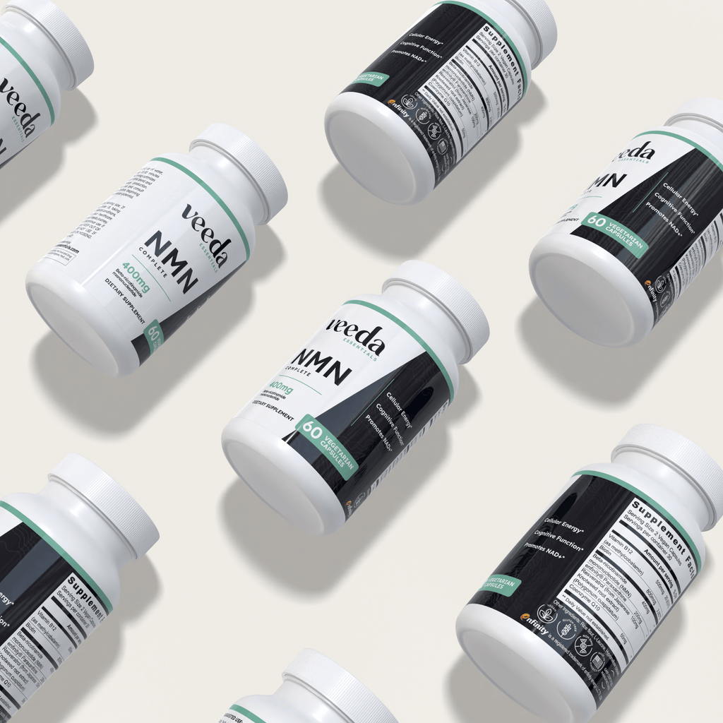Premium flatlay presentation of multiple Veeda Essentials NMN Complete bottles, designed to clearly showcase trusted labeling, clinically supported ingredients, NAD+ boosting effects, and enhanced cognitive and cellular health.